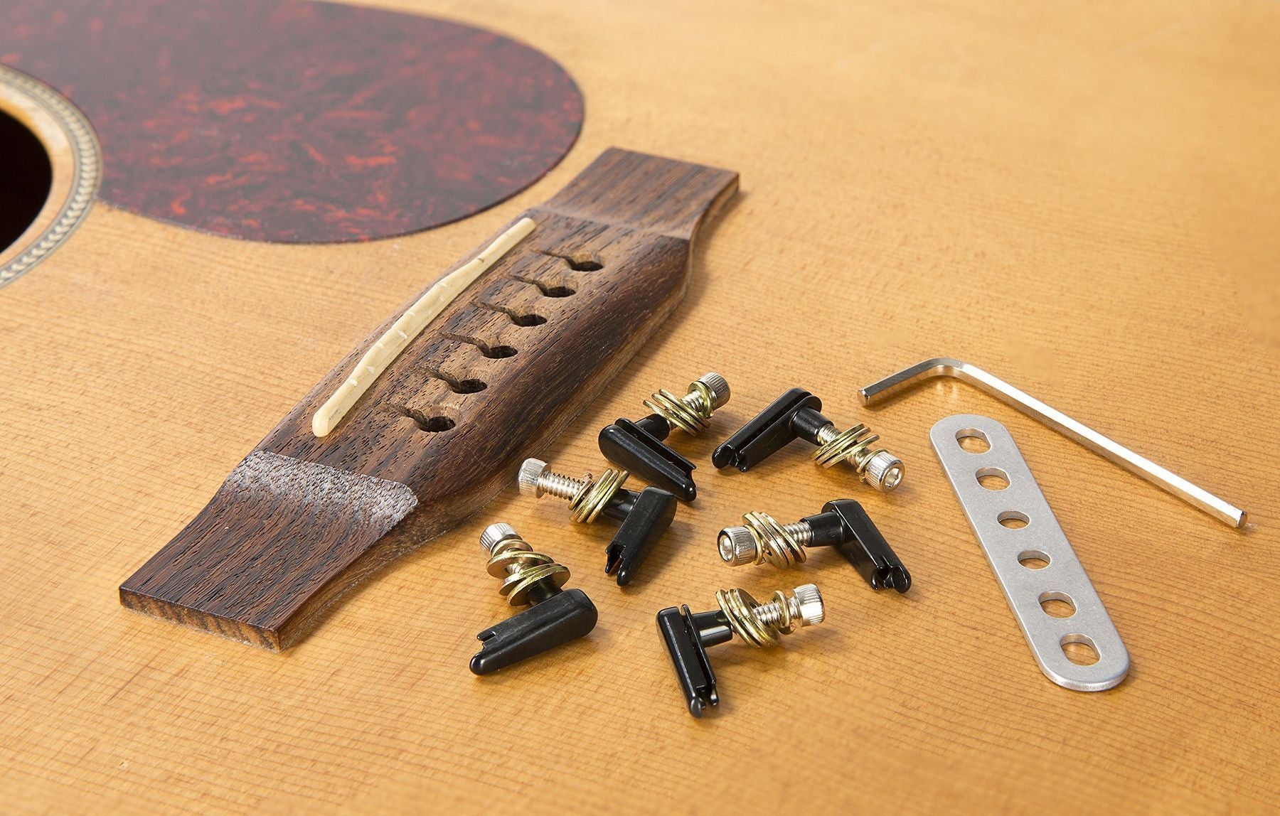 Power Pins 2.0 black-chrome acoustic-guitar bridge-pin system — bridge pins, power plate and Allen key beside an acoustic-guitar bridge — Slide 6 of 7